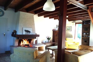 A cozy living room with a fireplace, wooden furniture, and a view of the outdoors. - Lovely Holiday Home in Sarzeau for 8 (Sarzeau)