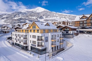 A hotel with multiple floors, balconies, and a sign indicating it is part of the Alps Resorts. - OFS_C_FW_2SZ_m.T._mH_FIS_13 (Fiss)