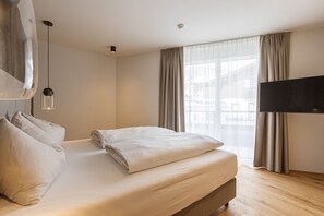A modern hotel room with a large bed, a flat-screen TV, and a large window with curtains. - OFS_C_FW_2SZ_m.T._mH_FIS_13 (Fiss)