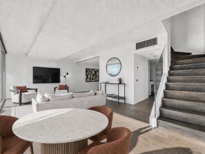 A modern living room with a sofa, a round table, and a staircase. - Harbour Muse - Stylish 2 or 3 Bedroom Apartment with Spectacular Harbour Views (Darlinghurst)