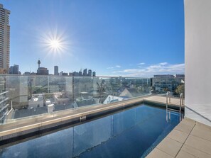 A rooftop pool with a glass barrier, city skyline views, and a clear sky. - Harbour Muse - Stylish 2 or 3 Bedroom Apartment with Spectacular Harbour Views (Darlinghurst)