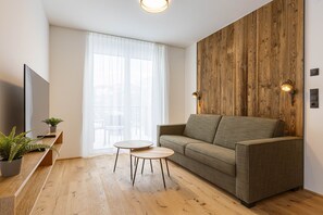 Ein modernes Wohnzimmer mit einer Couch, zwei runden Tischen, einem Fernseher und einer Holz-Akzentwand.
