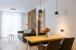 A modern living room with a sofa, a dining table, and a vase of flowers. - OFS_B_FW_1SZ_m.B._mH_FIS_8 (Fiss)