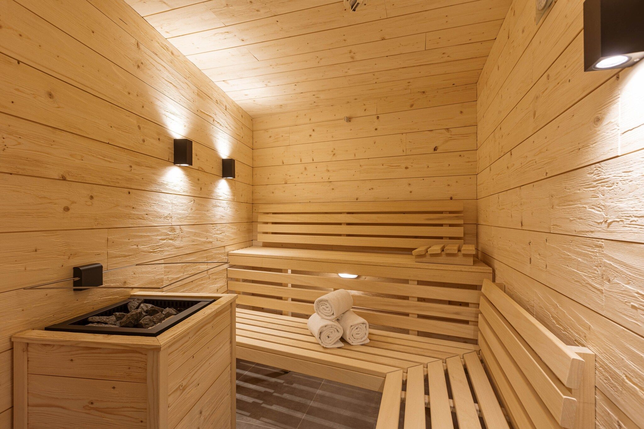 A wooden sauna with benches and a bench with towels.