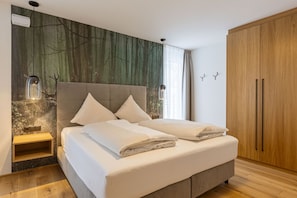 A modern bedroom with a bed, a nightstand, a wardrobe, and a wall with a forest-themed mural. - Fiss – Holiday apartment in the Alps (Fiss)