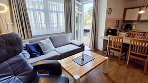 Un salon moderne comprenant un canapé, une table basse et un coin repas avec des chaises.