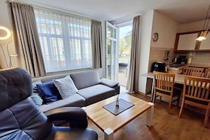 Ett modernt vardagsrum med en soffa, ett soffbord och en matplats med stolar.