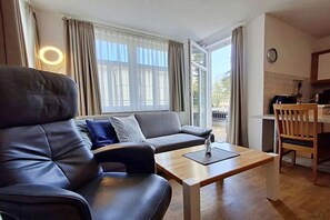 Ein modernes Wohnzimmer mit einer Ledersofa, einem Holztisch und Blick ins Freie.