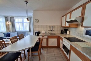 A compact kitchen with a dining area, a built-in oven, a microwave, and a sink. - House by the spa park (Ahlbeck (Seebad))