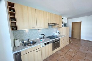 A modern kitchen with wooden cabinets, a stainless steel sink, and a built-in oven. - Apartment building Linquenda 10 (Ahlbeck (Seebad))