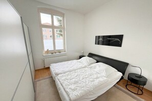 A bedroom with a double bed, a window, a radiator, and a wall-mounted artwork. - Holiday apartment Bülowstraße (Heringsdorf (Seebad))