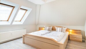 Un dormitorio con cama, mesitas de noche y un radiador.
