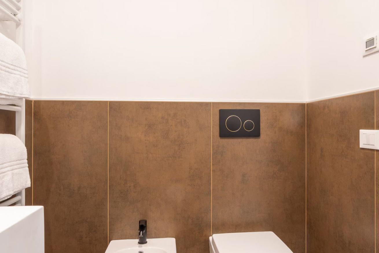 A bathroom with two sinks, a towel rack, and a wall-mounted control panel.
