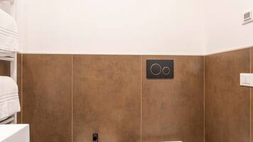 A bathroom with two sinks, a towel rack, and a wall-mounted control panel.