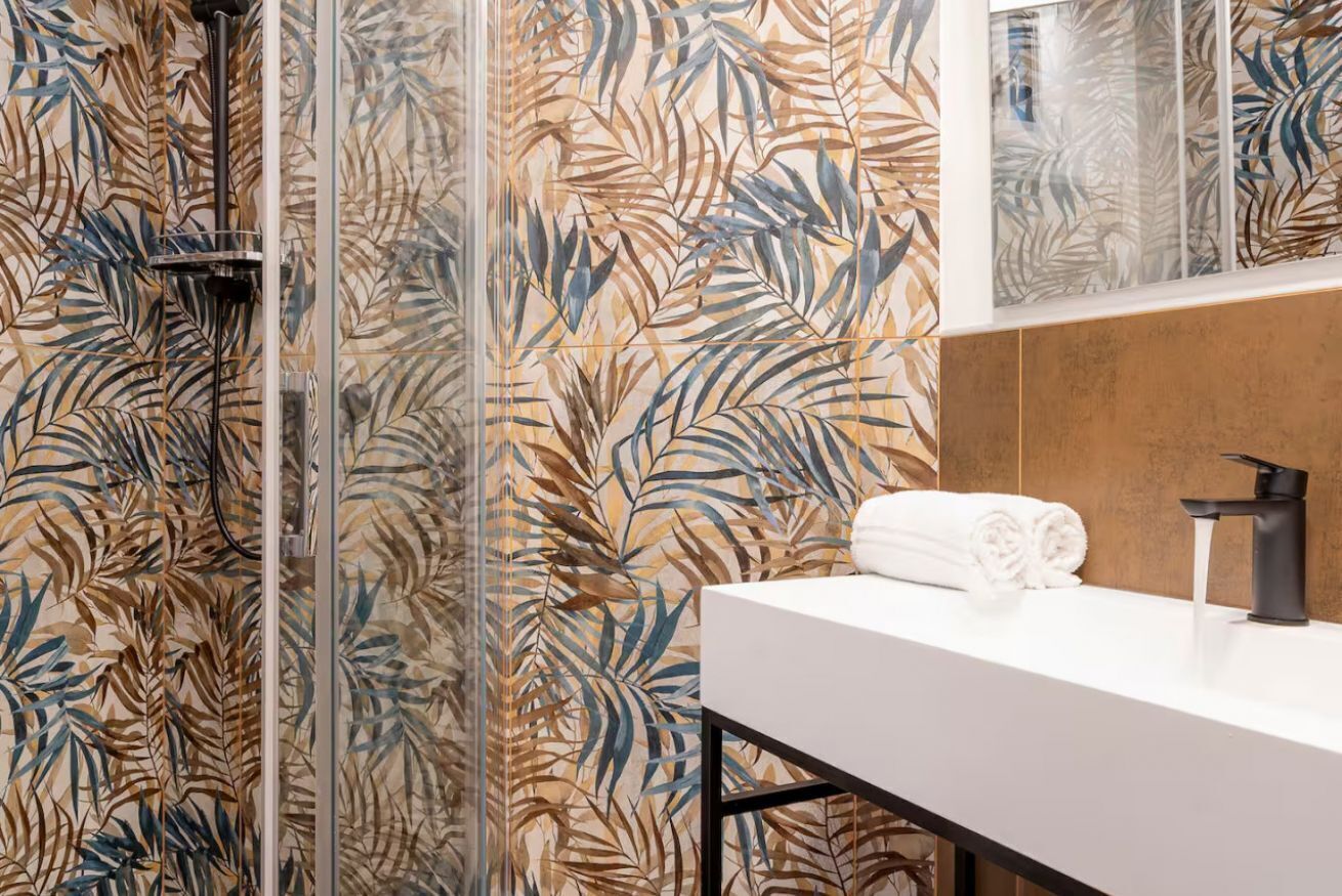 A bathroom with a shower, a white sink, and a towel.