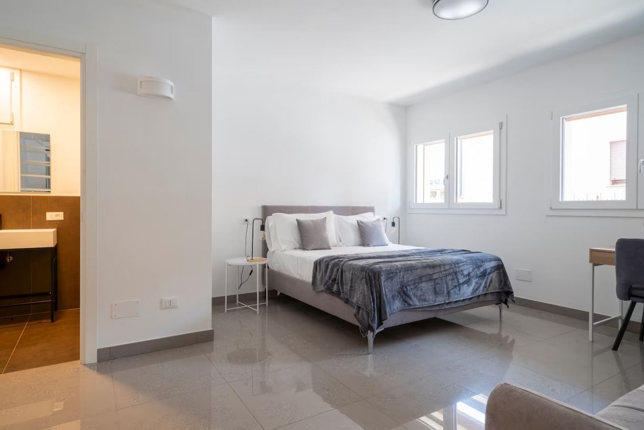 Una camera da letto con un letto, un comodino e una scrivania con una sedia.