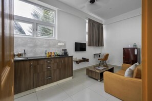 A modern kitchen with a built-in oven, a coffee maker, and a flat-screen TV mounted on the wall. - Wandr Hotel HSR Layout Sector 7 (Bengaluru)