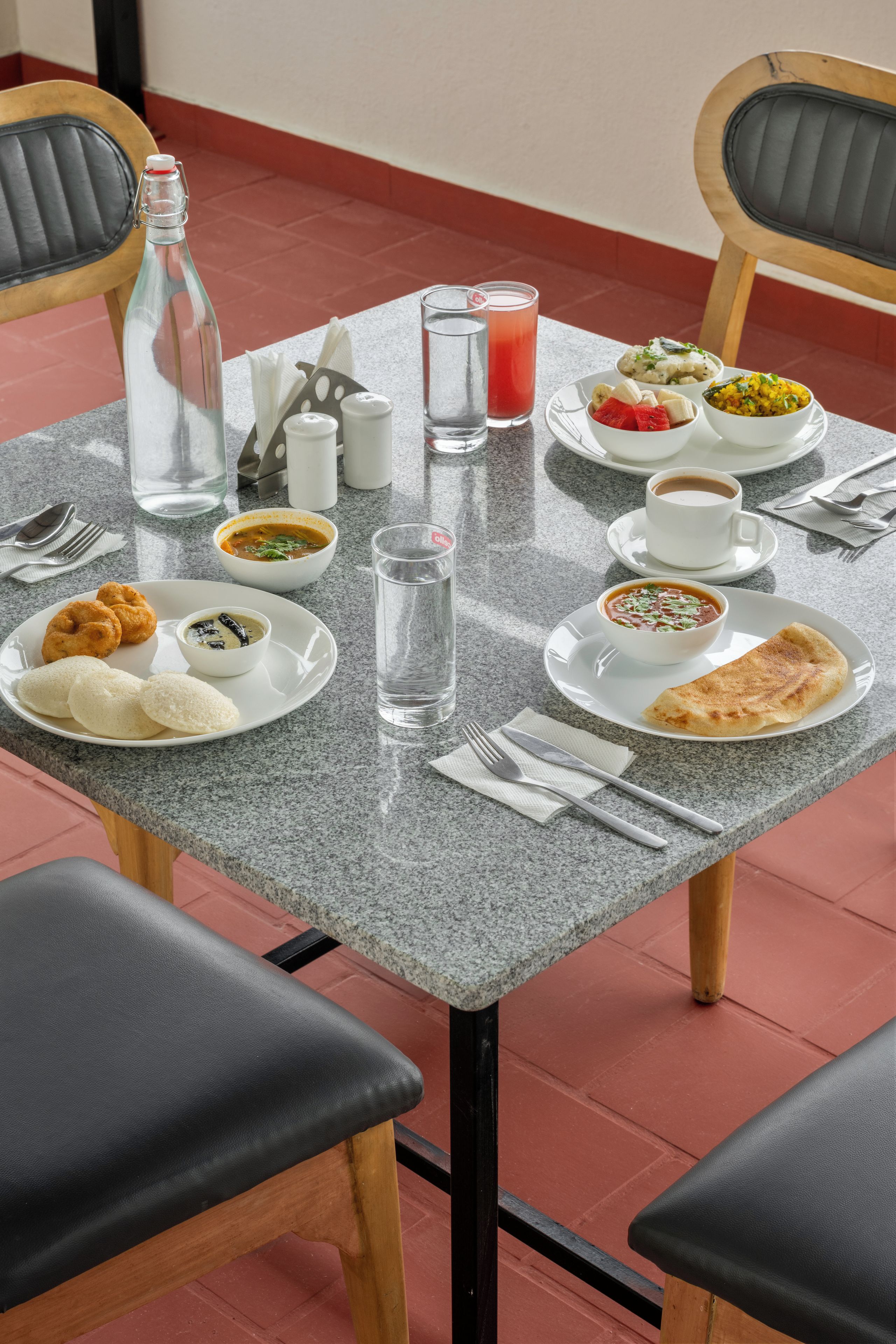 A dining table with plates of food, glasses of water, and a bottle.