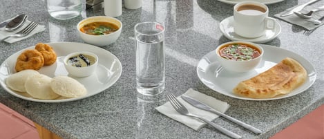 A dining table with plates of food, glasses of water, and a bottle.