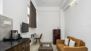 Un espacio habitable compacto con kitchenette, una TV de pantalla plana, un sofá y una mesa de centro.