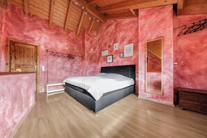 Quarto com cama, piso de madeira e teto inclinado.