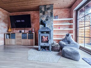 Ein gemütliches Wohnzimmer mit Kamin aus Stein, Holzmöbeln und einem großen Fenster.