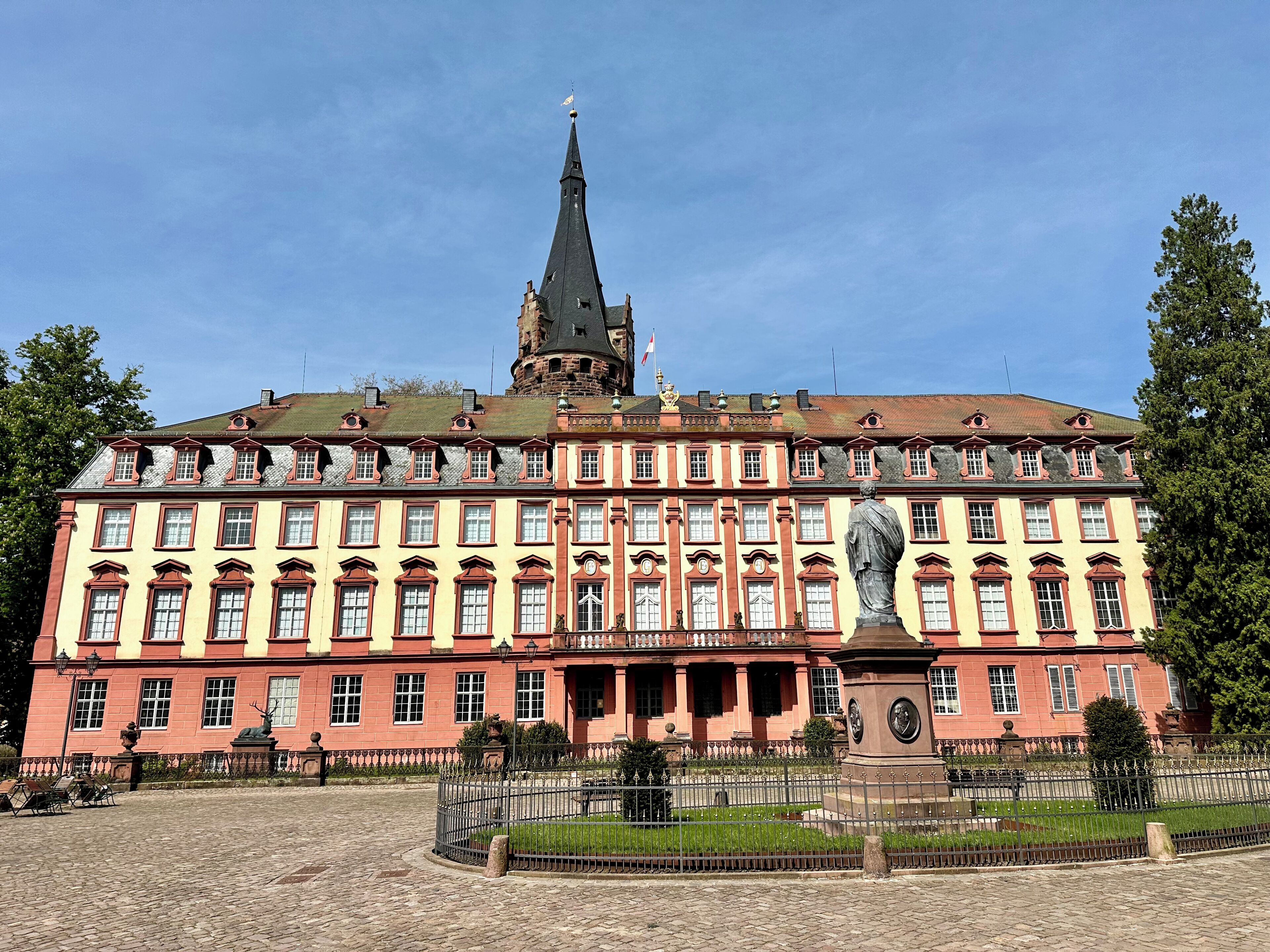 A historic building with a prominent tower and a statue in front.