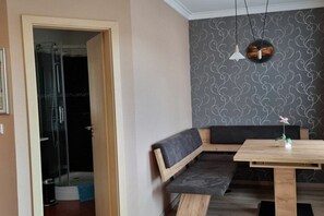 A modern bathroom with a glass shower enclosure, a wooden bench, and a small table with a vase. - Franzi holiday apartment (Ahlbeck (Seebad))