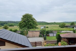 A residential area with a large tree, a fenced yard, and a building with a sloped roof. - Franzi holiday apartment (Ahlbeck (Seebad))