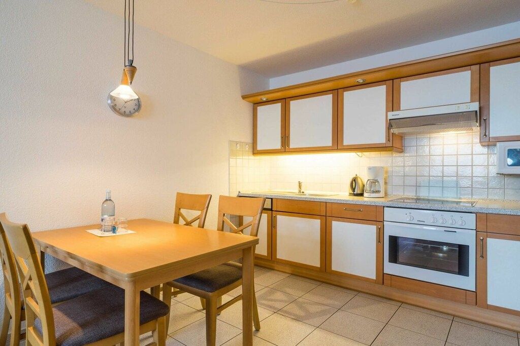 A kitchen with wooden cabinets, a built-in oven, and a dining table with chairs.