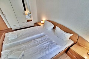 Een hotelkamer met een groot bed, een kledingkast en een nachtkastje met een lamp.