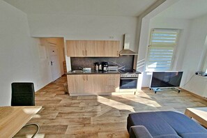 Eine kleine Küche mit Holzschränken, einem Herd und einem Fernseher.
