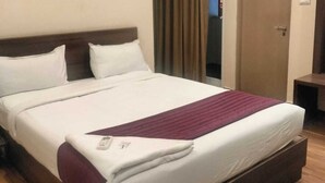 Una habitación de hotel con una cama, un aire acondicionado, una puerta y una cortina.