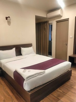 A hotel room with a bed, an air conditioning unit, a door, and a curtain. - Hotel Blue Pearl (Bengaluru)