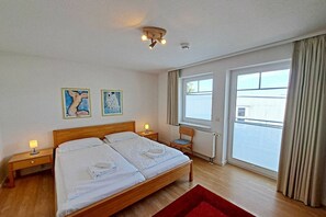 A bedroom with a double bed, two bedside tables, a window with curtains, and artwork on the wall. - Holiday apartment Brennert (Ahlbeck (Seebad))