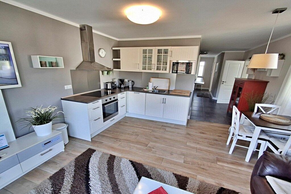 Una cocina moderna con armarios blancos, horno empotrado y una isla central.