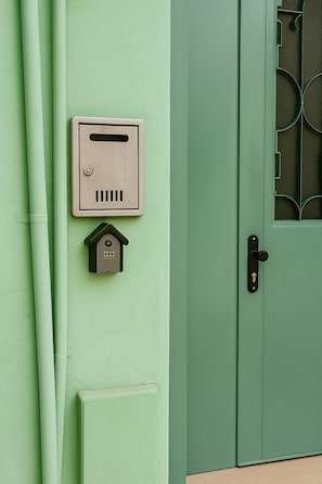 Une porte verte dotée d’un clavier pour ouvrir la serrure et d’une fente pour le courrier.