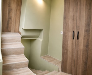 Eine Treppe mit Holzvertäfelung, eine hellgrüne Wand und eine Holztür mit zwei Griffen.