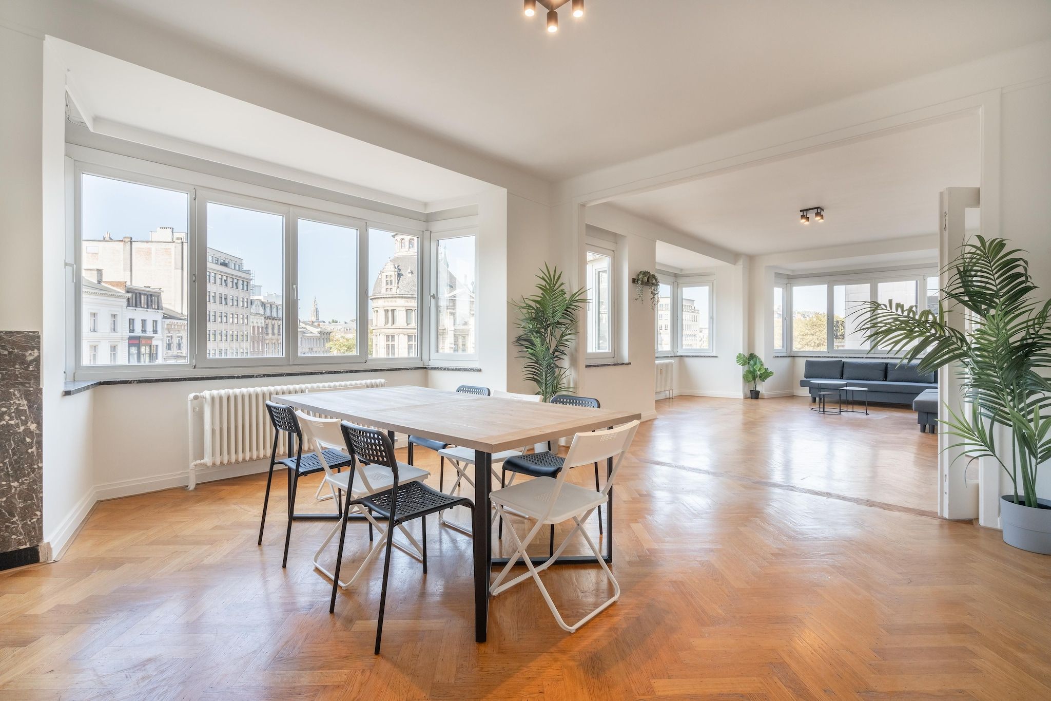 A spacious living area with a large dining table, multiple chairs, and a sofa.
