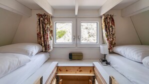 Ein Zimmer mit zwei Betten, einem Vorhangfenster, einer Nachttischlampe und einem kleinen Heizgerät.