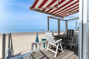 Een terras aan het strand met een tafel en stoelen, met uitzicht op de oceaan.