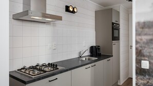 A modern kitchen with a gas stove, stainless steel sink, and white cabinetry. - Villa in Schaijk near Forest & Water (Schaijk)