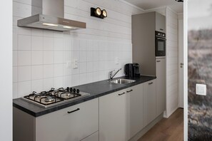 Een moderne keuken met een gasfornuis, een roestvrijstalen spoelbak en witte kasten.