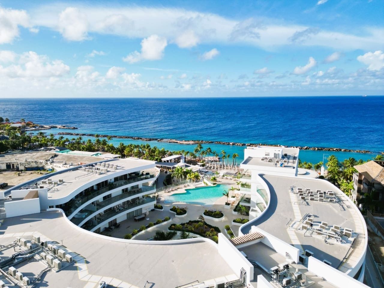 Un resort con piscina central, varios balcones y vista al océano.