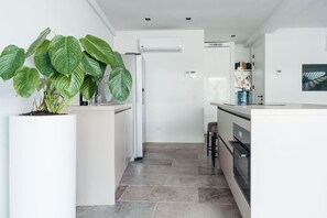 Une cuisine moderne dotée d’un îlot central, d’une grande plante en pot et d’un système de climatisation intégré.