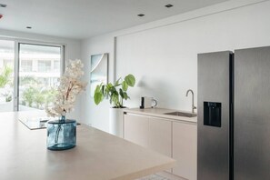 Une cuisine moderne équipée d’un réfrigérateur en acier inoxydable, d’un évier et d’un plan de travail agrémenté d’un vase de fleurs.