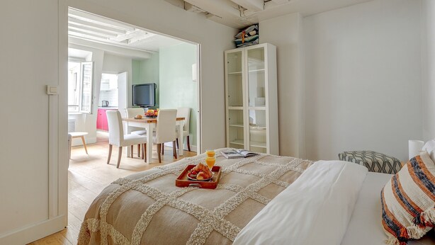 Una camera da letto con un letto, un comodino con un vassoio per la colazione, un armadio e vista sulla stanza adiacente.