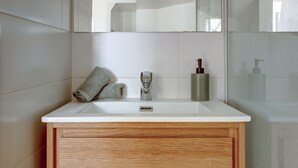 Un bagno con lavandino bianco, mobile contenitore in legno e uno specchio sopra.