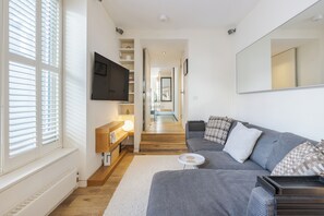 Ein modernes Wohnzimmer mit einem grauen Sofa, einem kleinen runden Couchtisch und einem großen Spiegel an der Wand.
