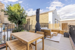 Eine Terrasse im Freien mit Holzmöbeln, einem Tisch und einem überdachten Sitzbereich.